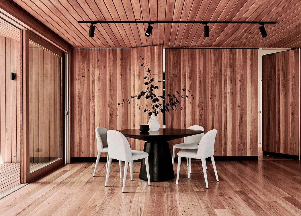 Sleek, modern dining space with wooden walls, track lighting, and a minimalist black table.