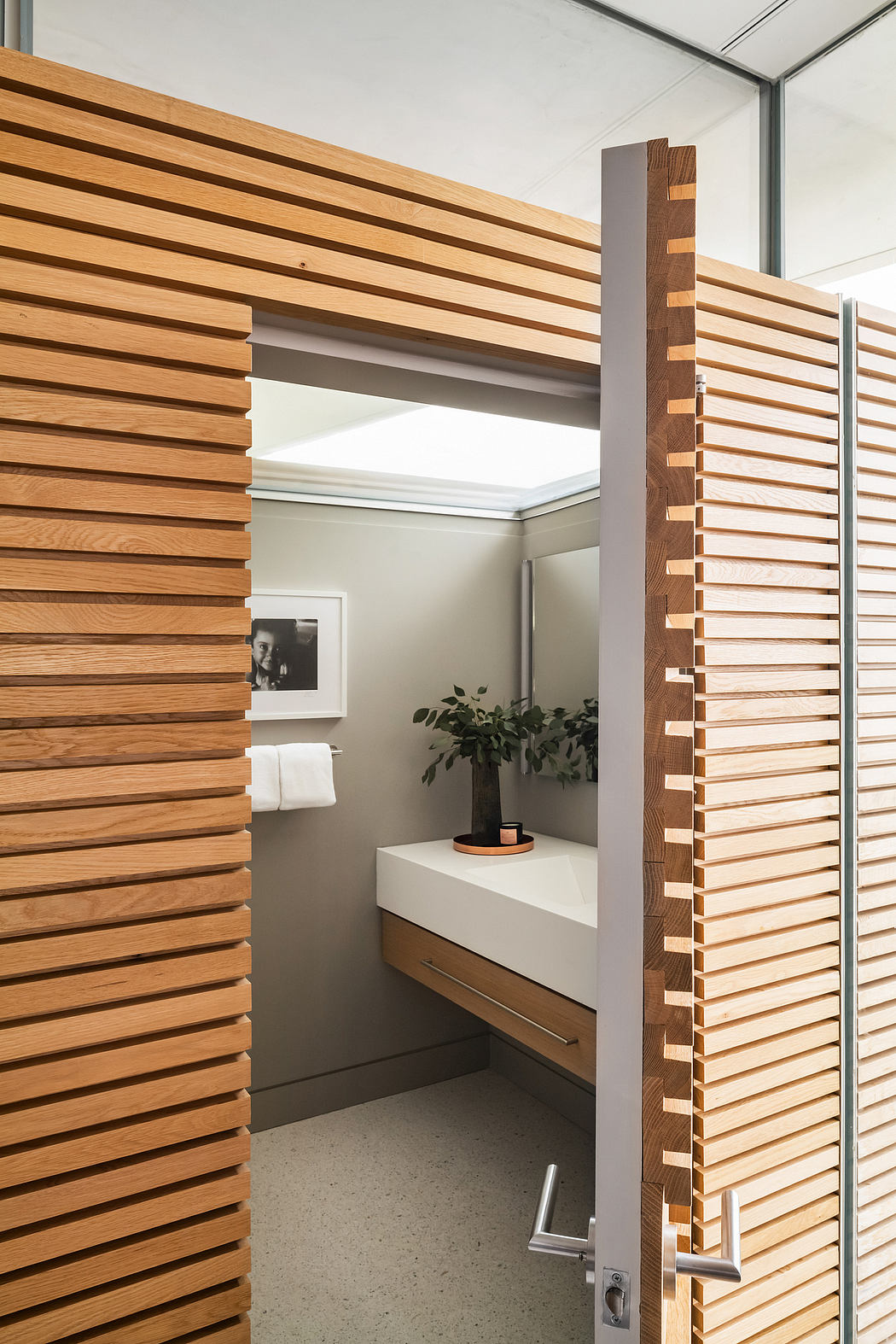 Wooden slat walls and built-in storage in a modern, minimalist bathroom design.