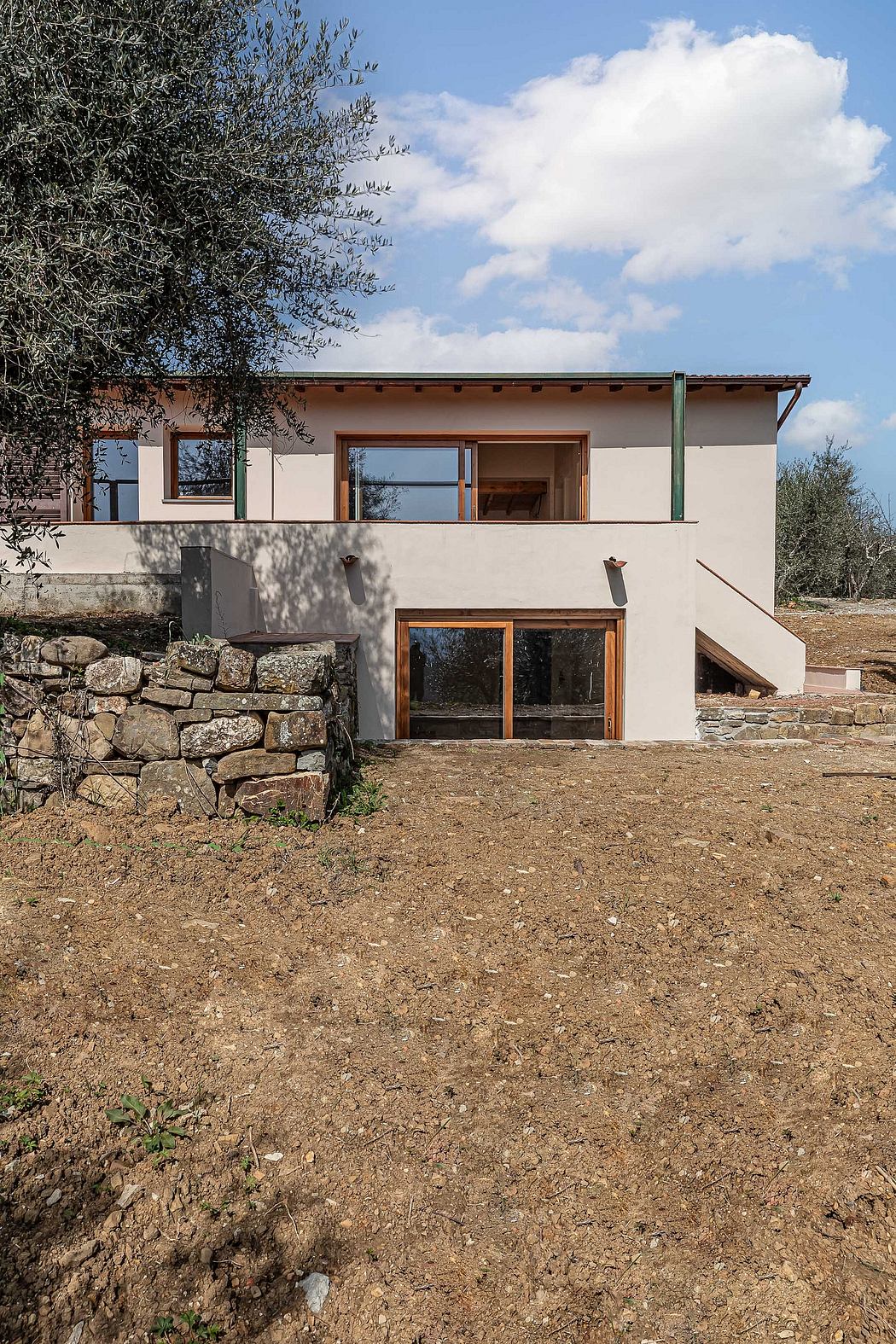 Rustic Mediterranean-style home with stone walls, wooden beams, and large windows.