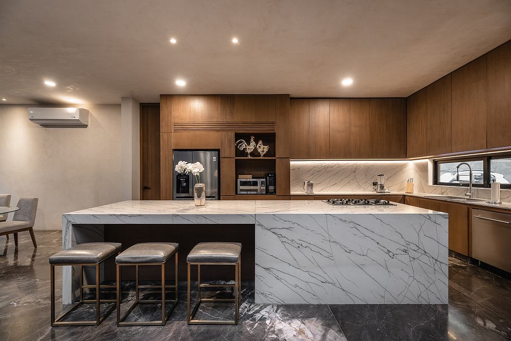 A modern kitchen with sleek wooden cabinetry, a large marble island, and stainless steel appliances.