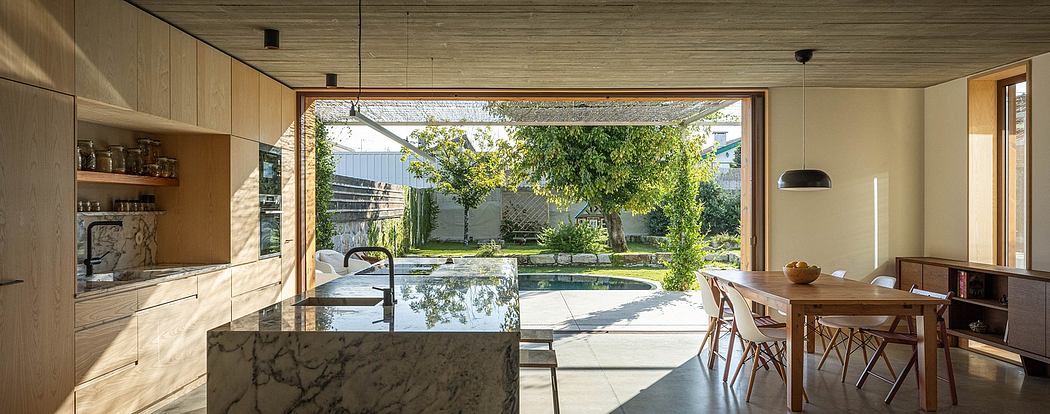 Well-designed open kitchen with marble countertop, expansive windows overlooking lush garden.