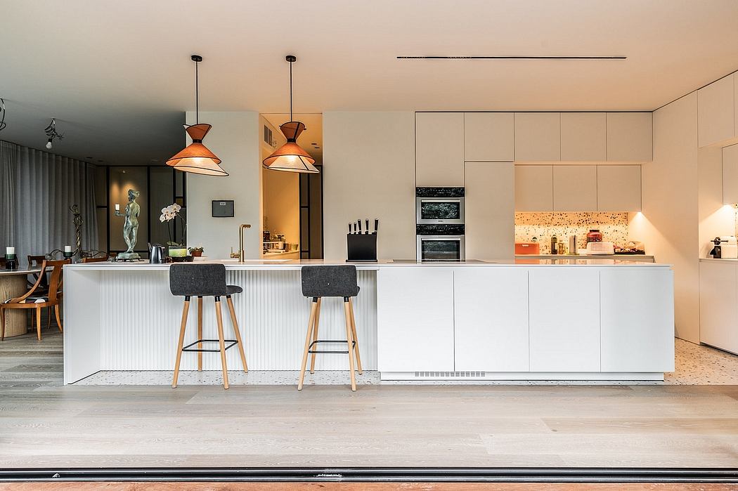 Modern kitchen interior with white cabinetry, pendant lights, and bar seating.