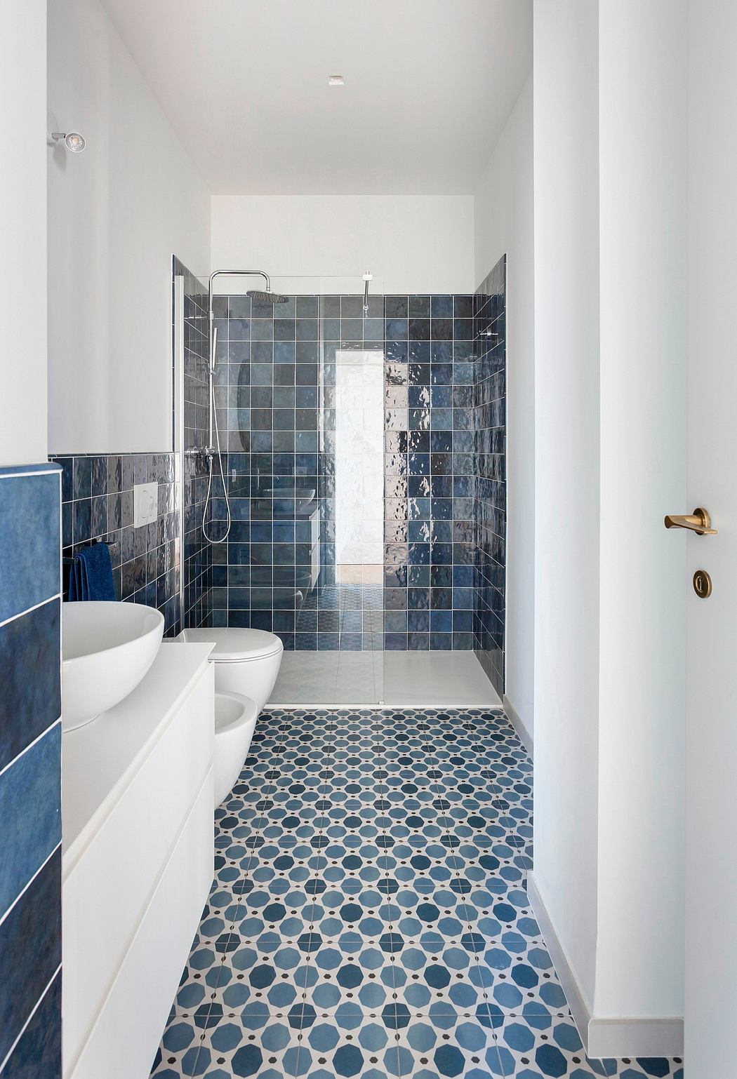 A modern bathroom with a tiled shower and patterned floor tiles, showcasing a clean, minimalist design.