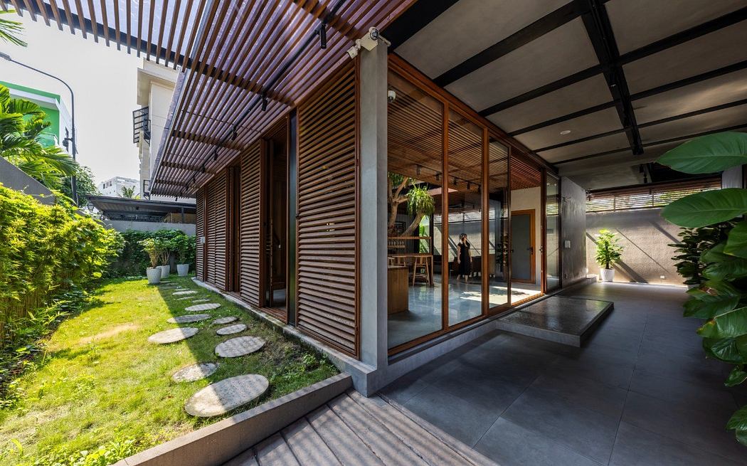 Tropical-inspired outdoor courtyard with wooden slats, large glass doors, and stone path.