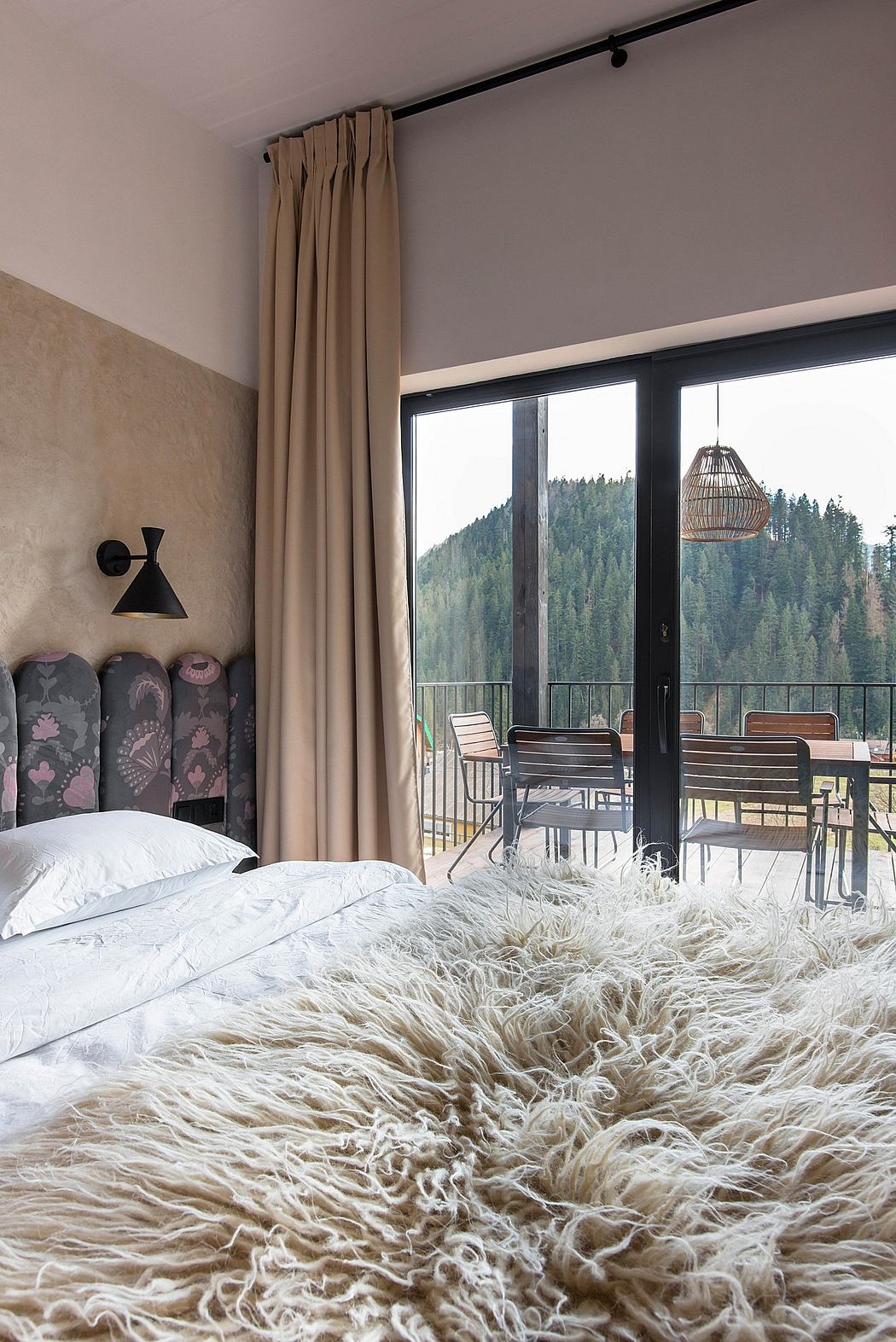 Cozy bedroom with mountain view, plush fur rug, and modern furnishings.