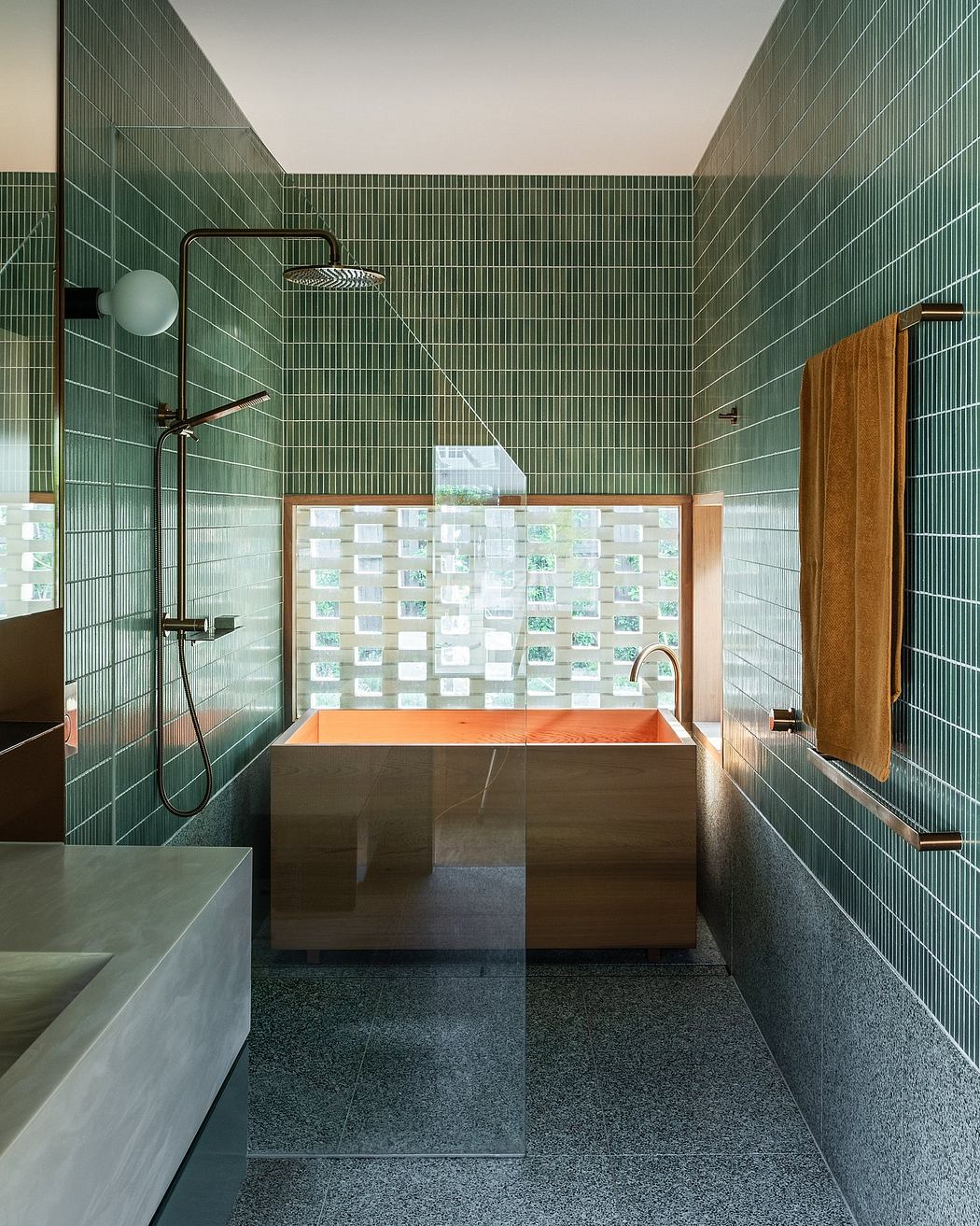 Sleek, modern bathroom with striking green tiled walls, a freestanding orange bathtub, and a minimalist shower.
