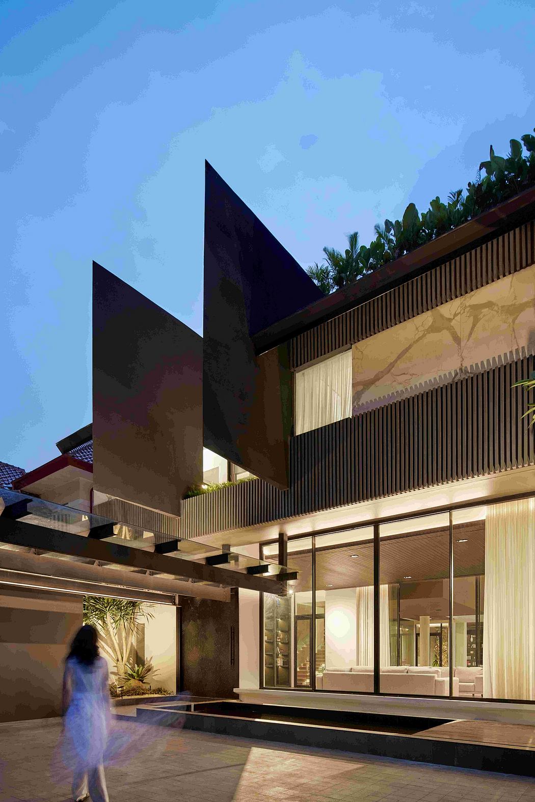 Sleek, angular architectural design featuring a glass facade, wood paneling, and water feature.