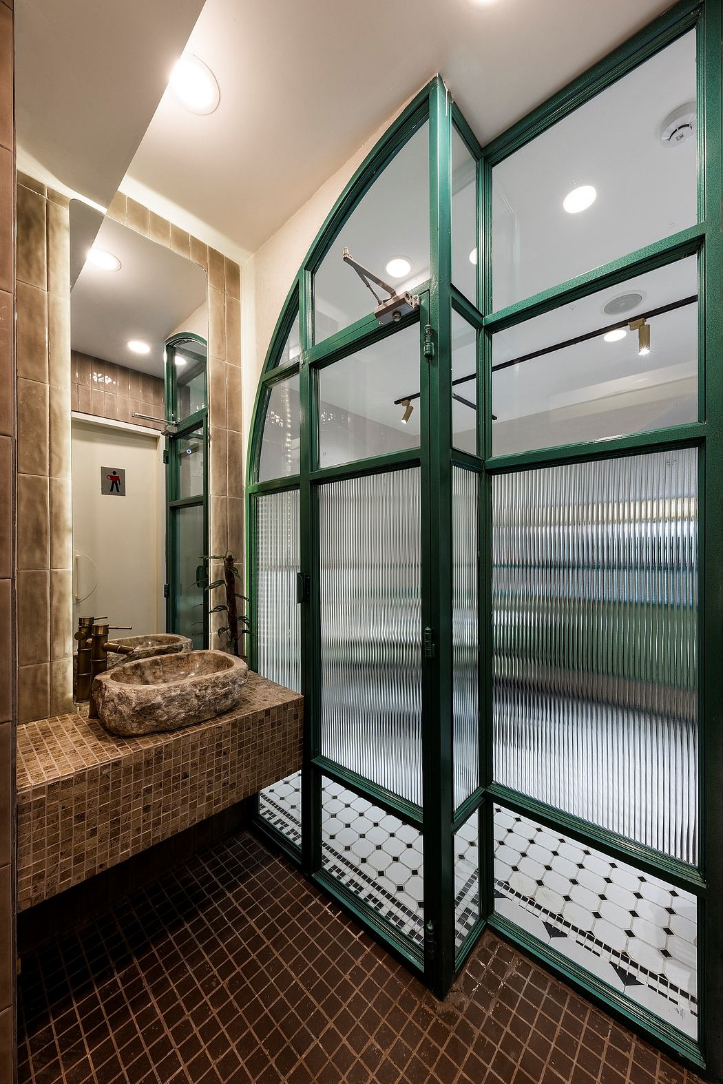 A modern bathroom featuring glass walls, textured tiles, and a central stone sink.