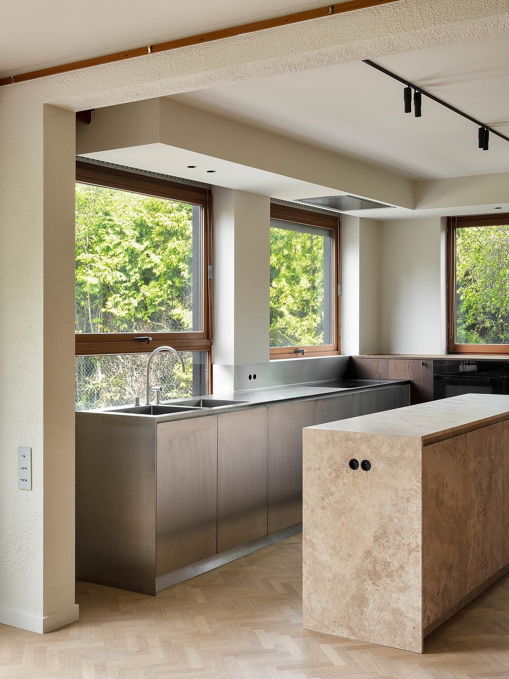 Sleek, minimalist kitchen with stainless steel cabinets, marble countertop, and large windows overlooking lush foliage.