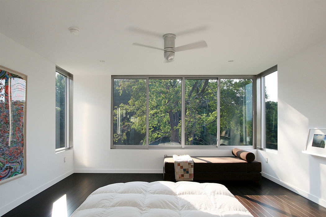 Bright, modern bedroom with expansive windows overlooking lush greenery.