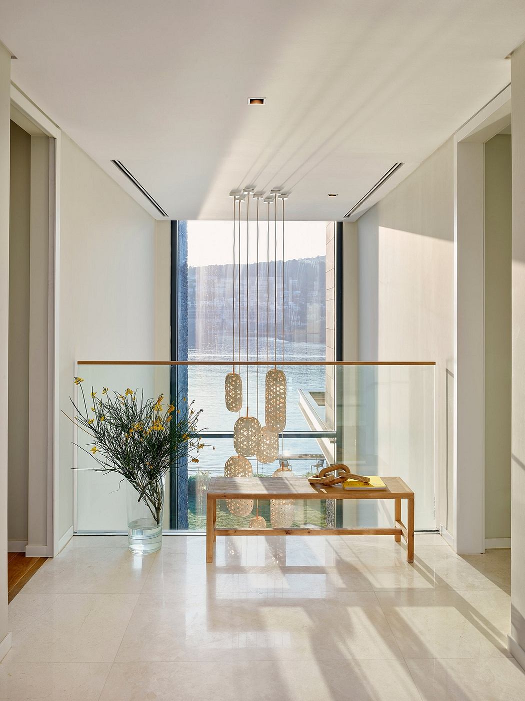 Minimalist foyer with sleek glass walls, pendant lamps, and wooden console table.