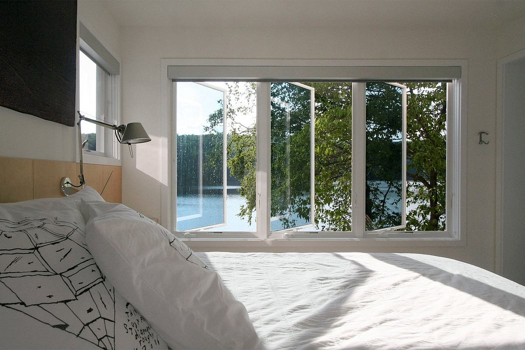A bright, spacious bedroom with floor-to-ceiling windows overlooking lush greenery and water.