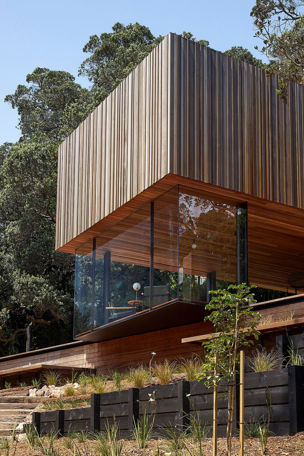 Sleek wood and metal facade with expansive glass windows overlooking a lush landscape.