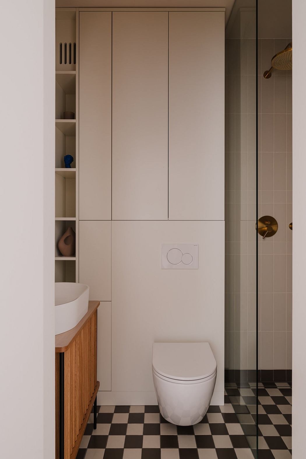 Minimalist bathroom with built-in storage, checkered flooring, and sleek white fixtures.