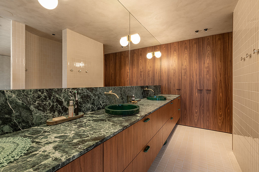 A modern bathroom with wood paneling, green marble countertops, and circular vessel sinks.