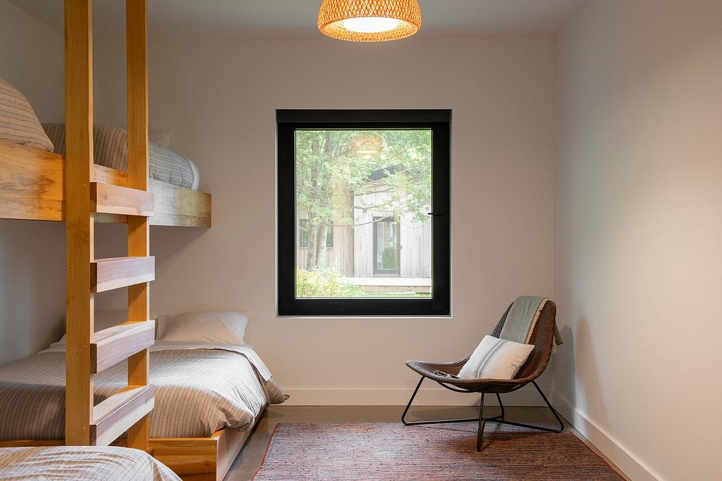 A cozy bedroom with wooden bunk beds, a woven pendant light, and a framed view of a lush outdoor scene.