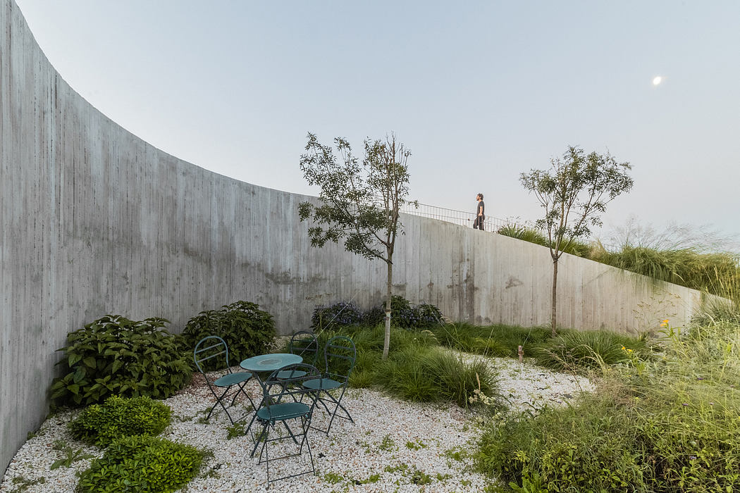 Minimalist outdoor seating area surrounded by lush vegetation and concrete walls.