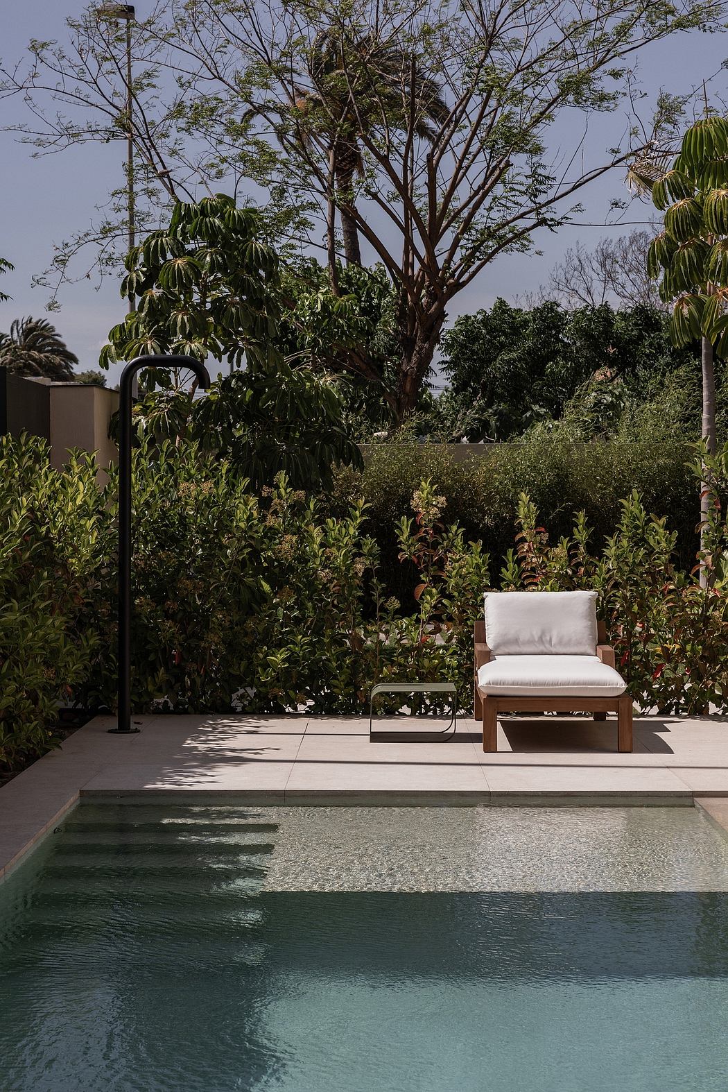 A tranquil outdoor setting with a plunge pool, concrete patio, and a cozy lounge chair.