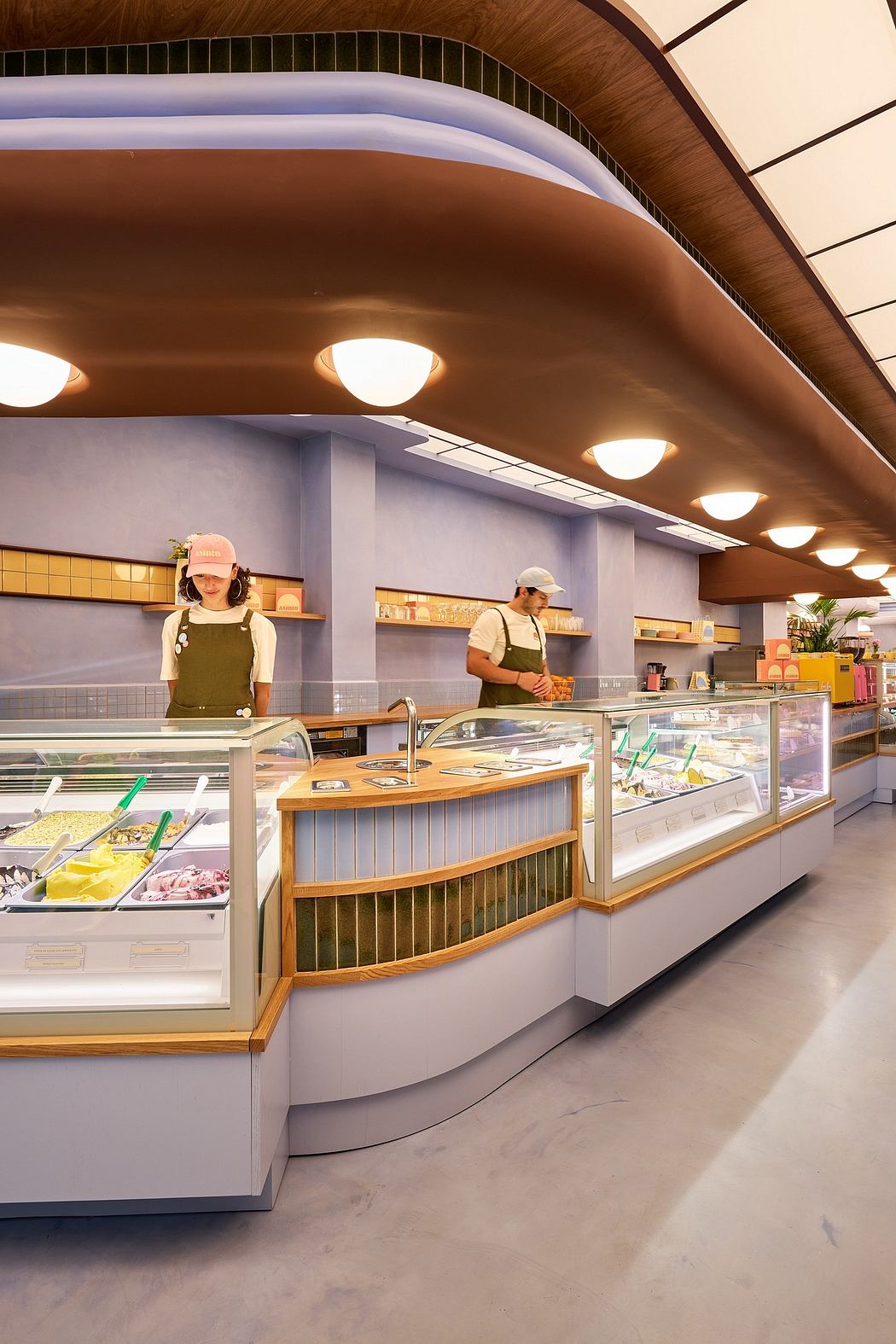A modern deli-style interior with curved wooden counters, lit shelves, and tiled walls.