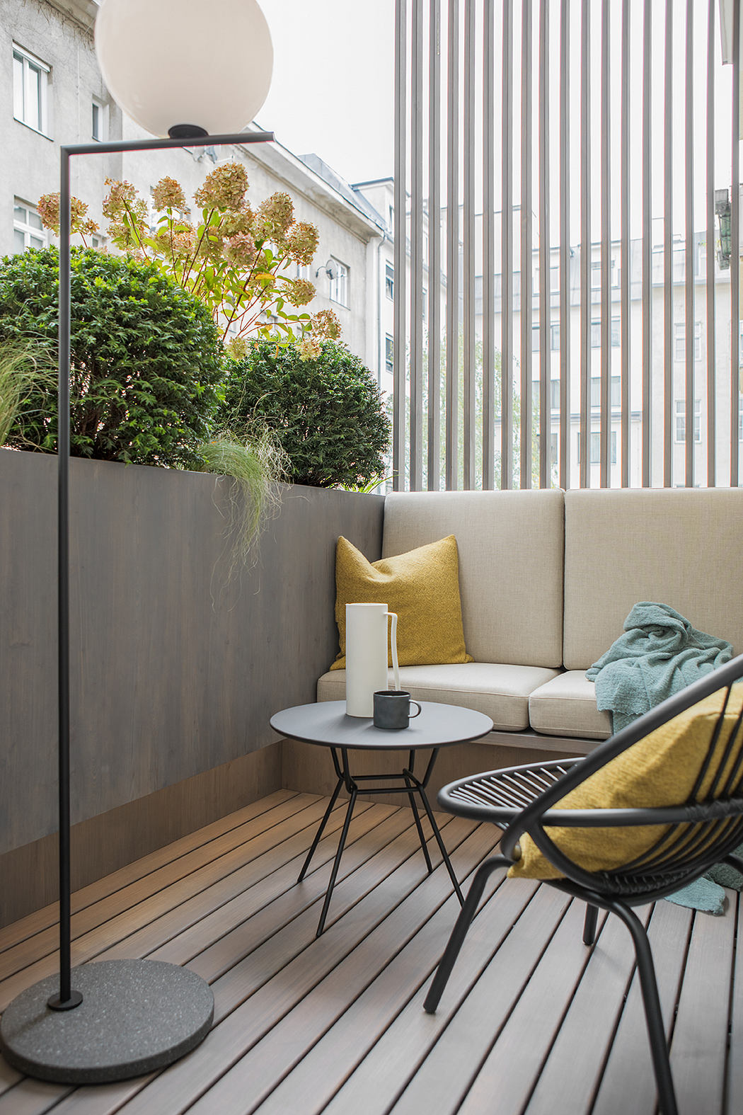Cozy balcony space with plush seating, side table, and decorative foliage.