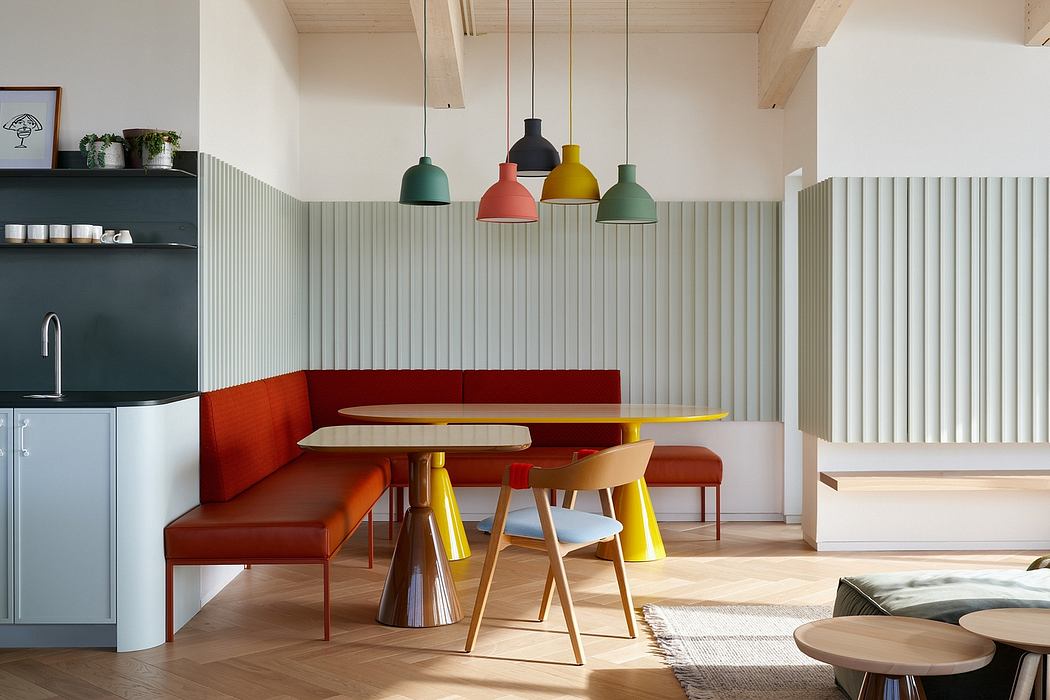 Vibrant, modern kitchen-dining area with colorful pendant lights, wood furniture, and textured wall paneling.