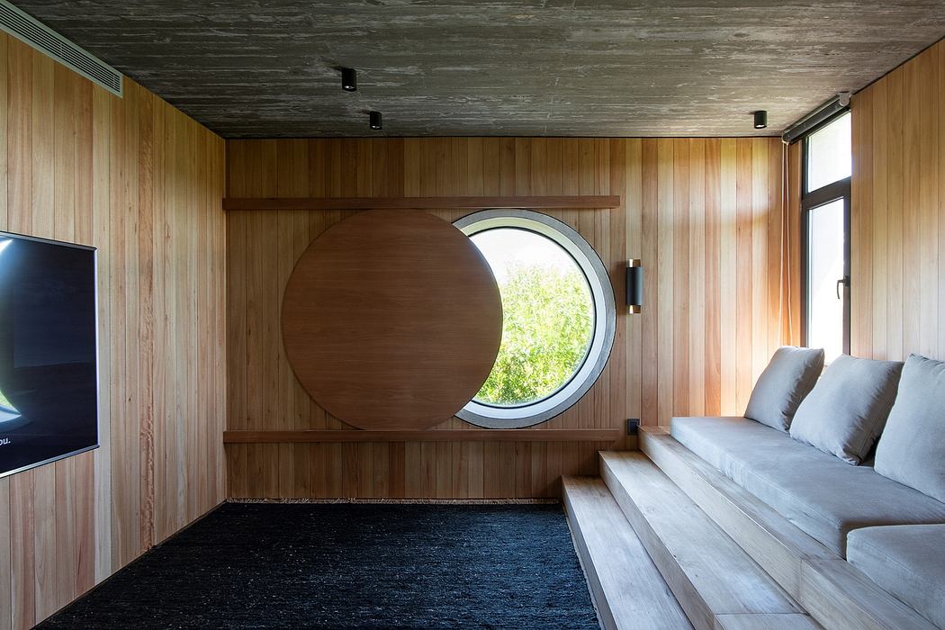 A cozy interior with warm wooden panels, a circular window, and a comfortable seating area.