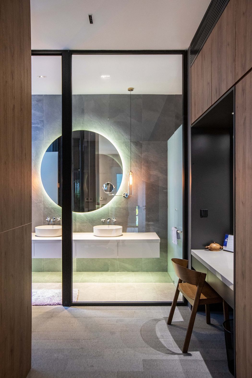 A modern bathroom with a large circular mirror, sleek vanity, and minimalist lighting.