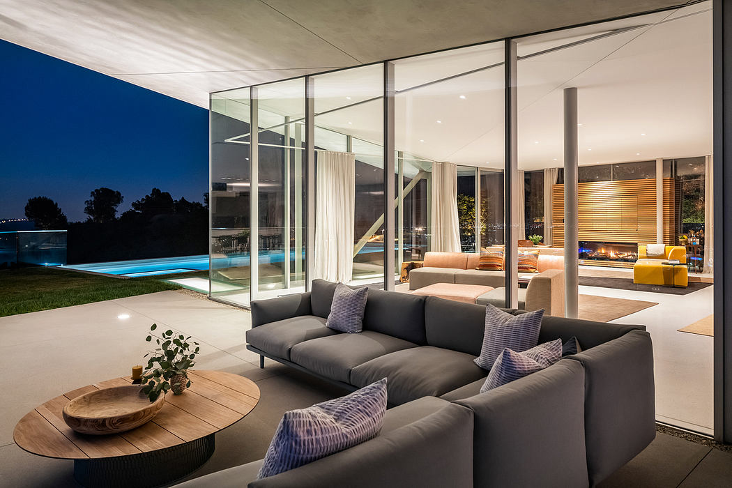 Expansive modern living room with floor-to-ceiling windows, plush seating, and pool view.