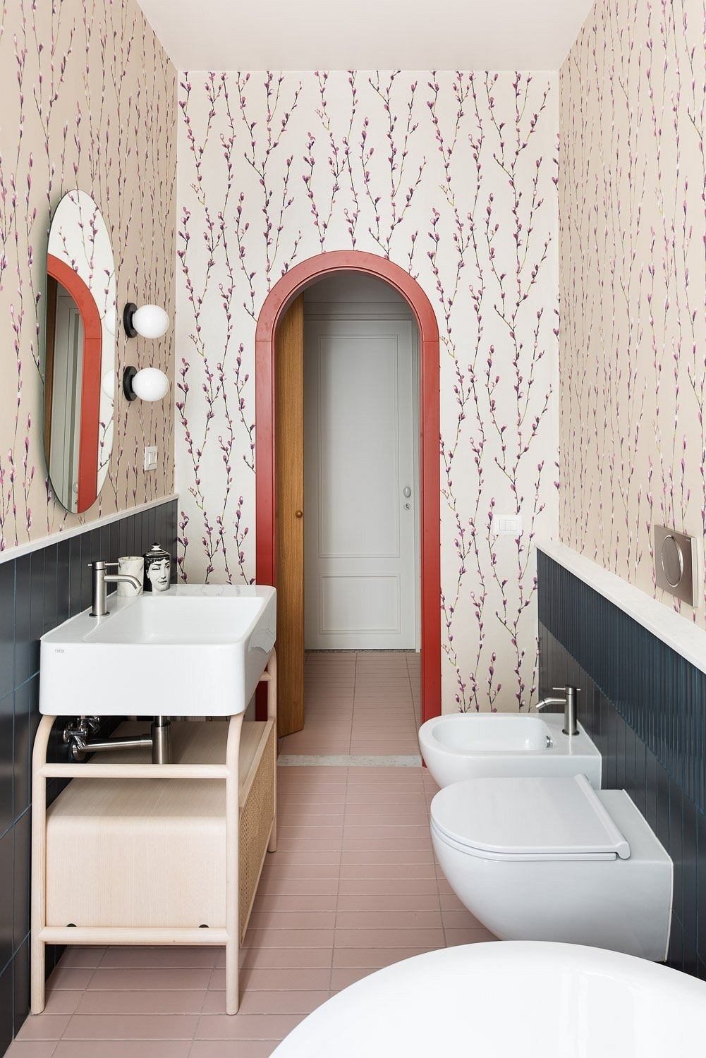 Cozy bathroom with arched doorway, floral wallpaper, and contemporary fixtures.