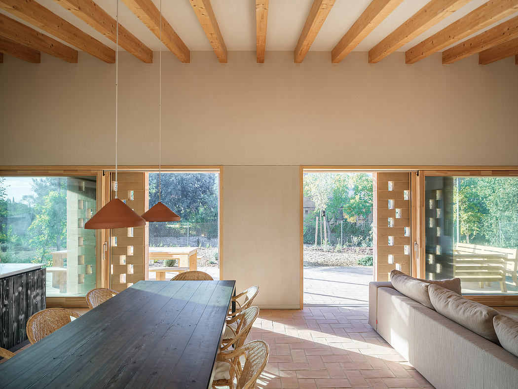 Warm-toned wooden ceiling beams, large windows, and a rustic dining table in a spacious room.