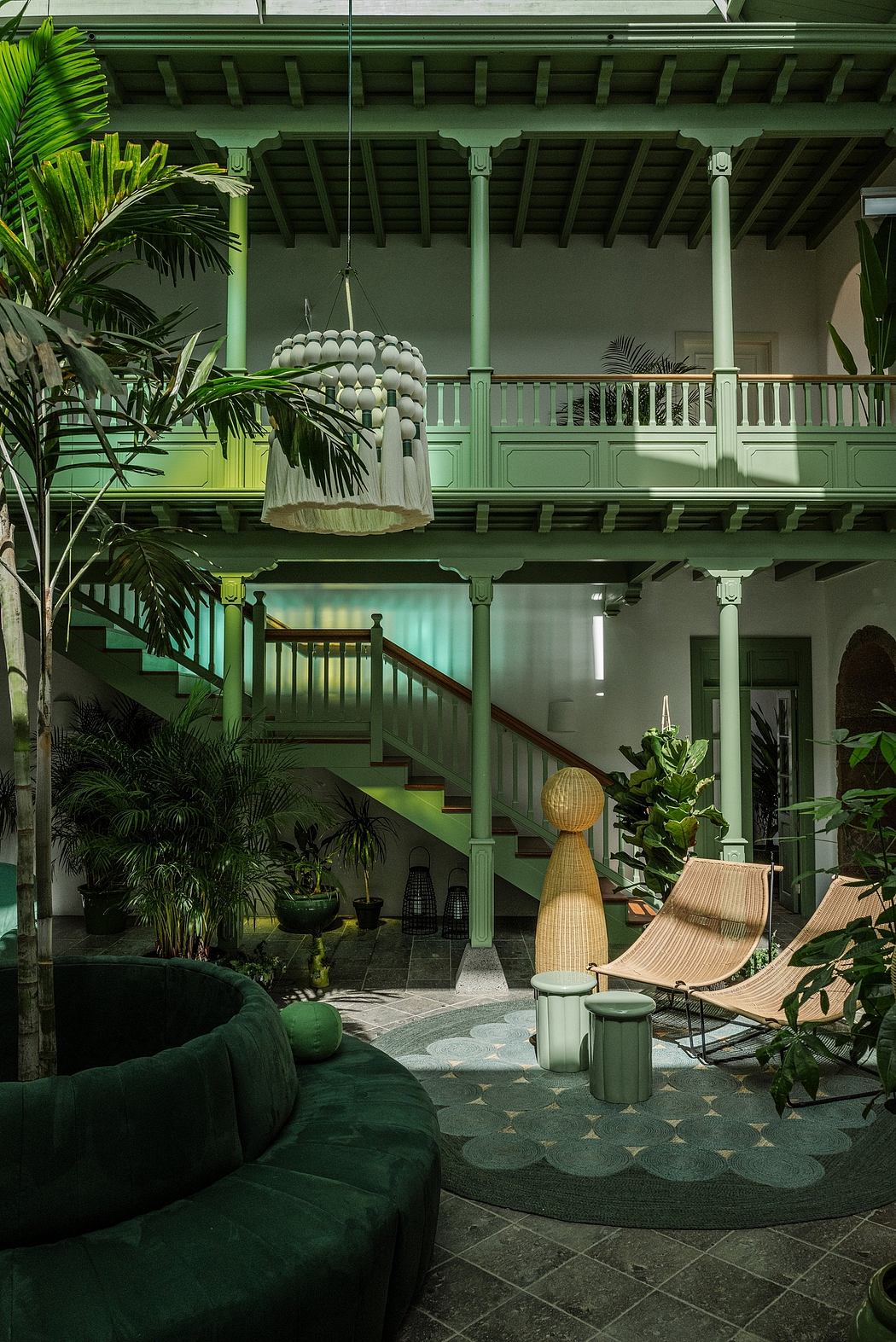 Elegant tropical-inspired indoor atrium with ornate green architecture and furnishings.