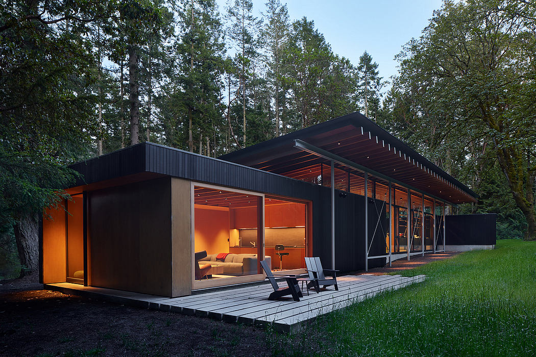 Striking modern cabin nestled in lush forest, featuring sleek black exterior and warm lighting.