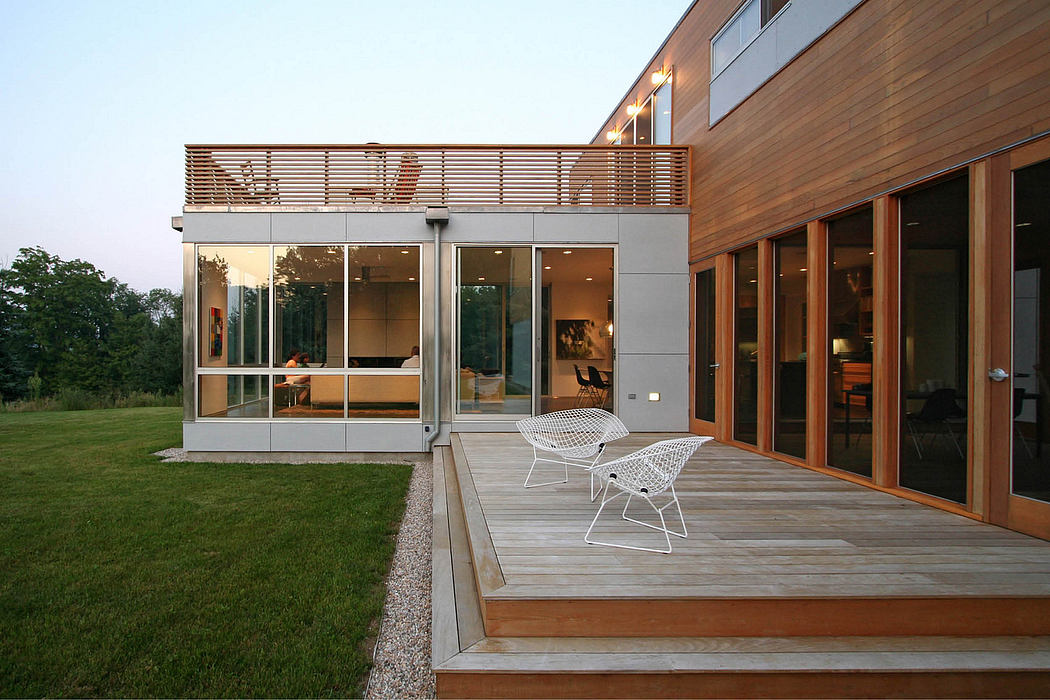 Modern glass and wood exterior with a covered porch and minimalist patio furniture.