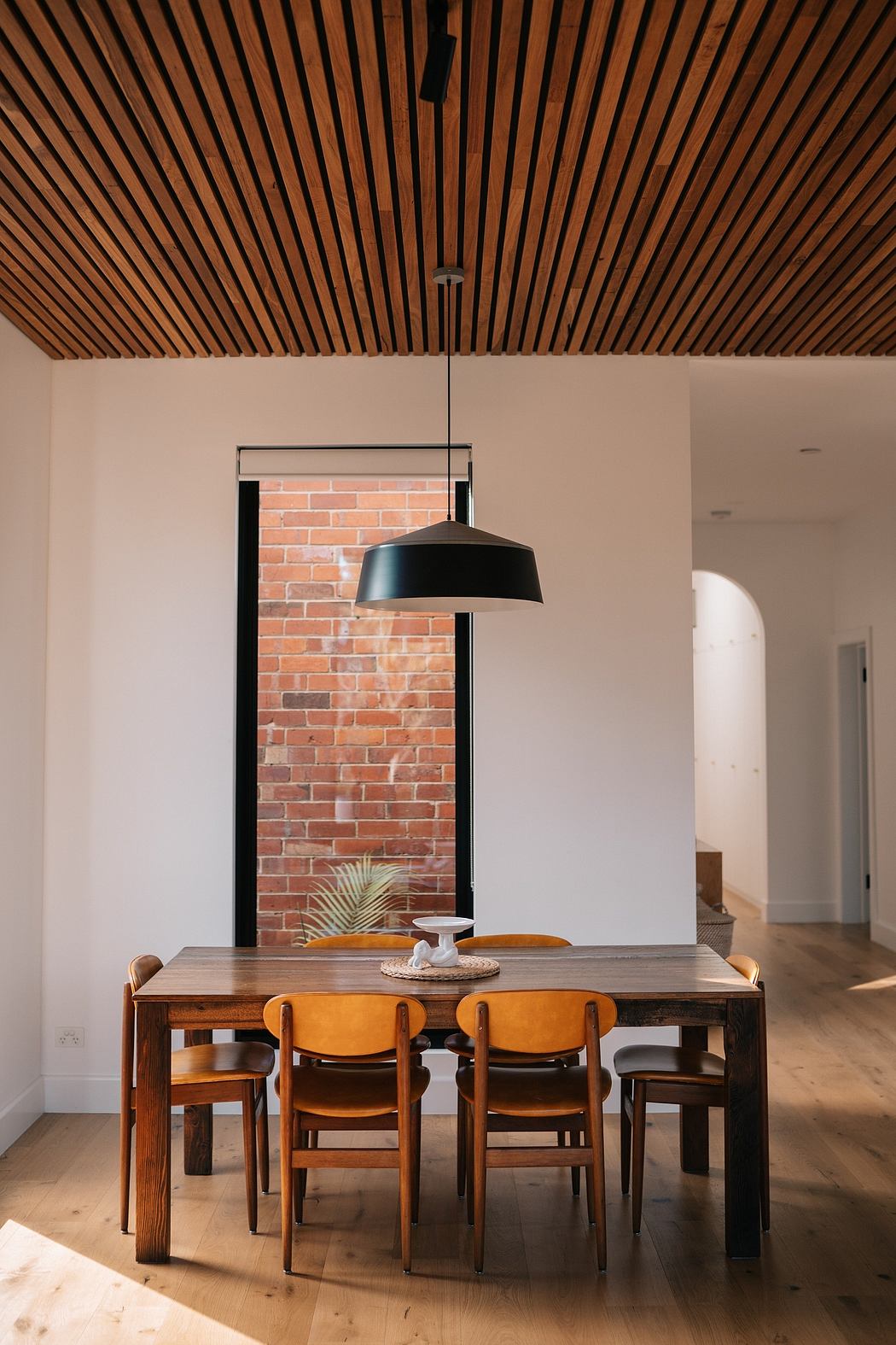 Rustic wooden ceiling, modern lighting, and brick accent wall in cozy dining space.