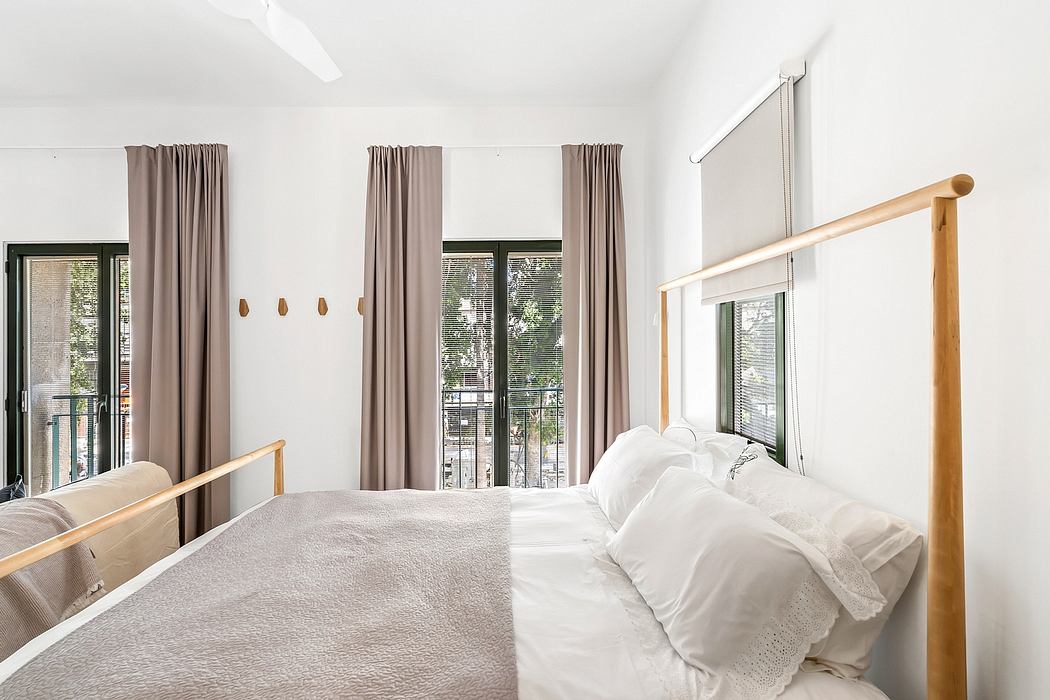 Cozy bedroom with large windows, wooden furnishings, and neutral color palette.