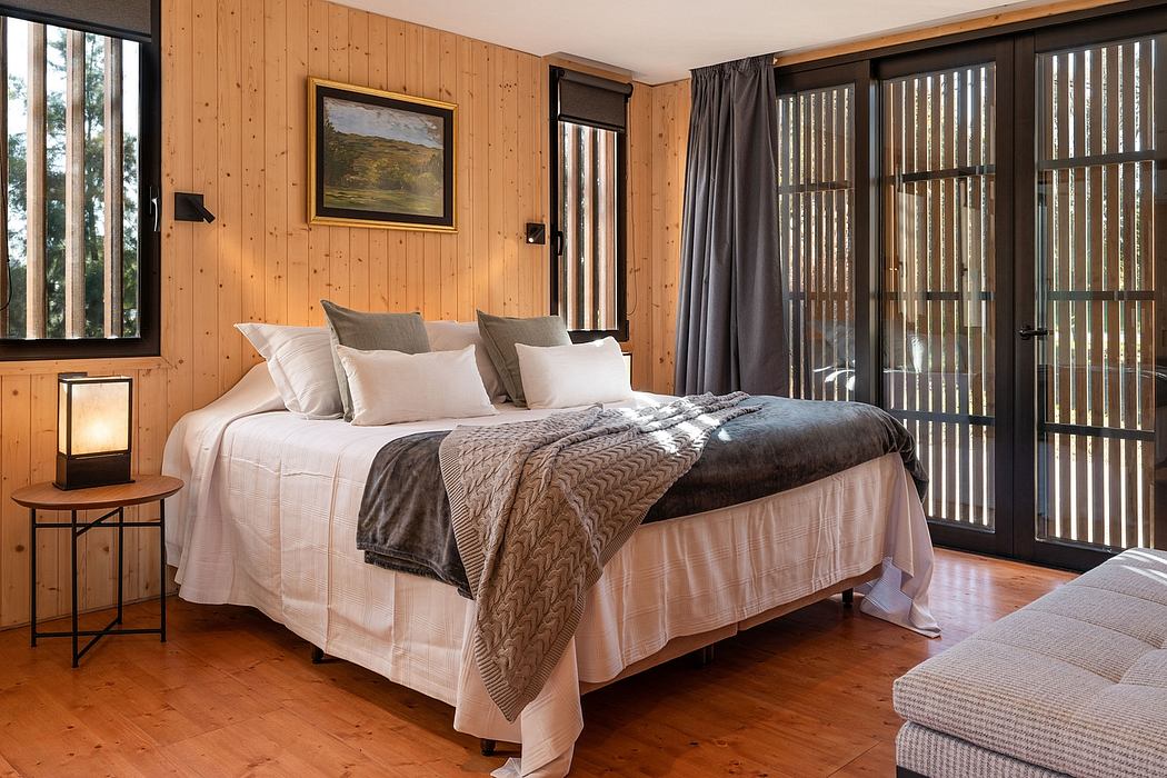 Cozy cabin interior with wooden walls, large bed, and sliding glass doors leading outdoors.