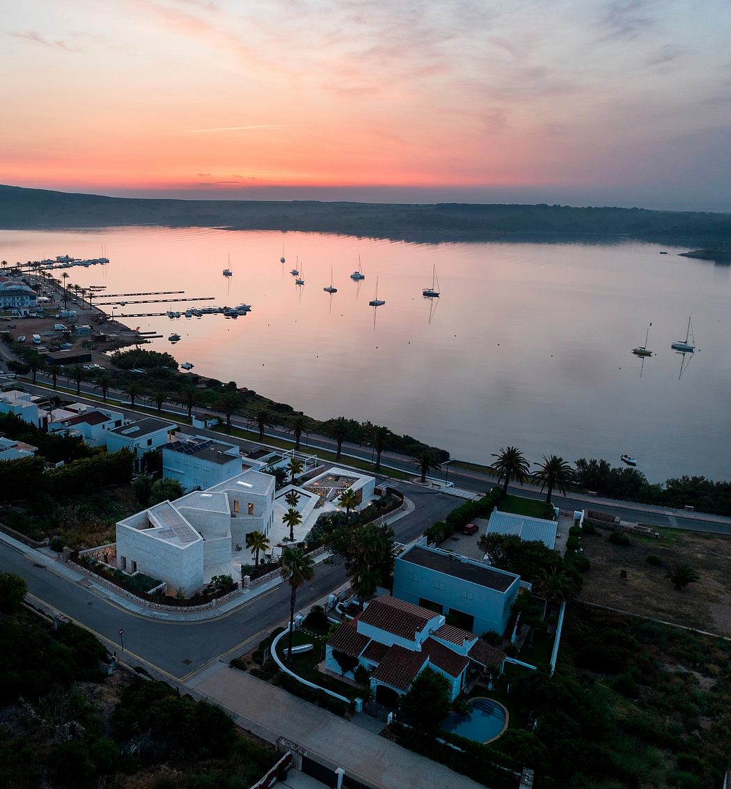 A coastal town at sunset, with a marina, boats, and colorful architecture.