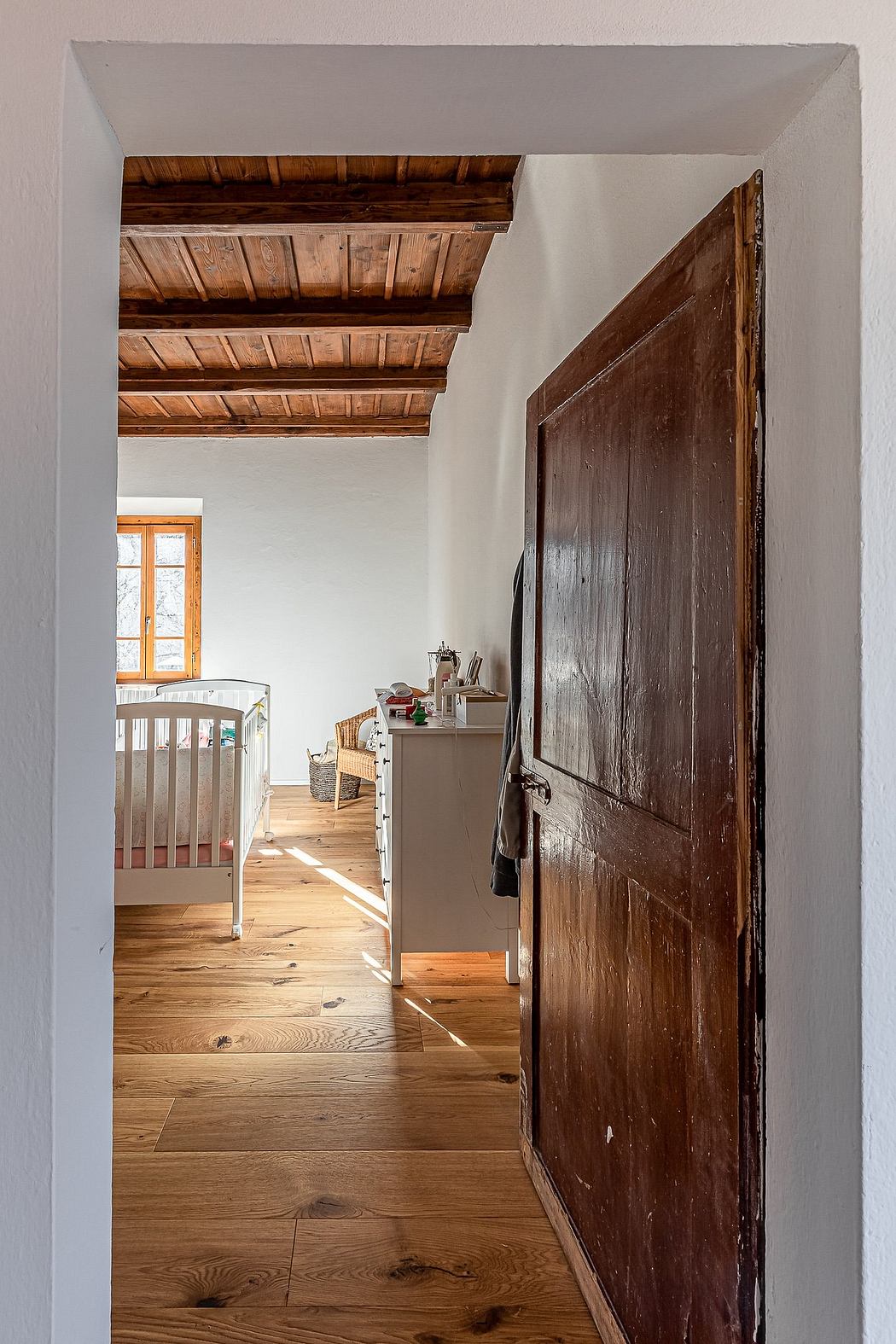 Rustic wooden ceiling and floor, with an old wooden door leading to another room.