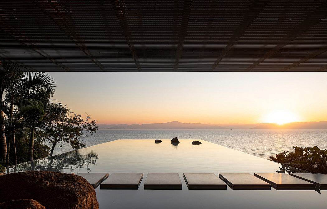 Tranquil infinity pool overlooking serene ocean sunset, surrounded by tropical foliage.