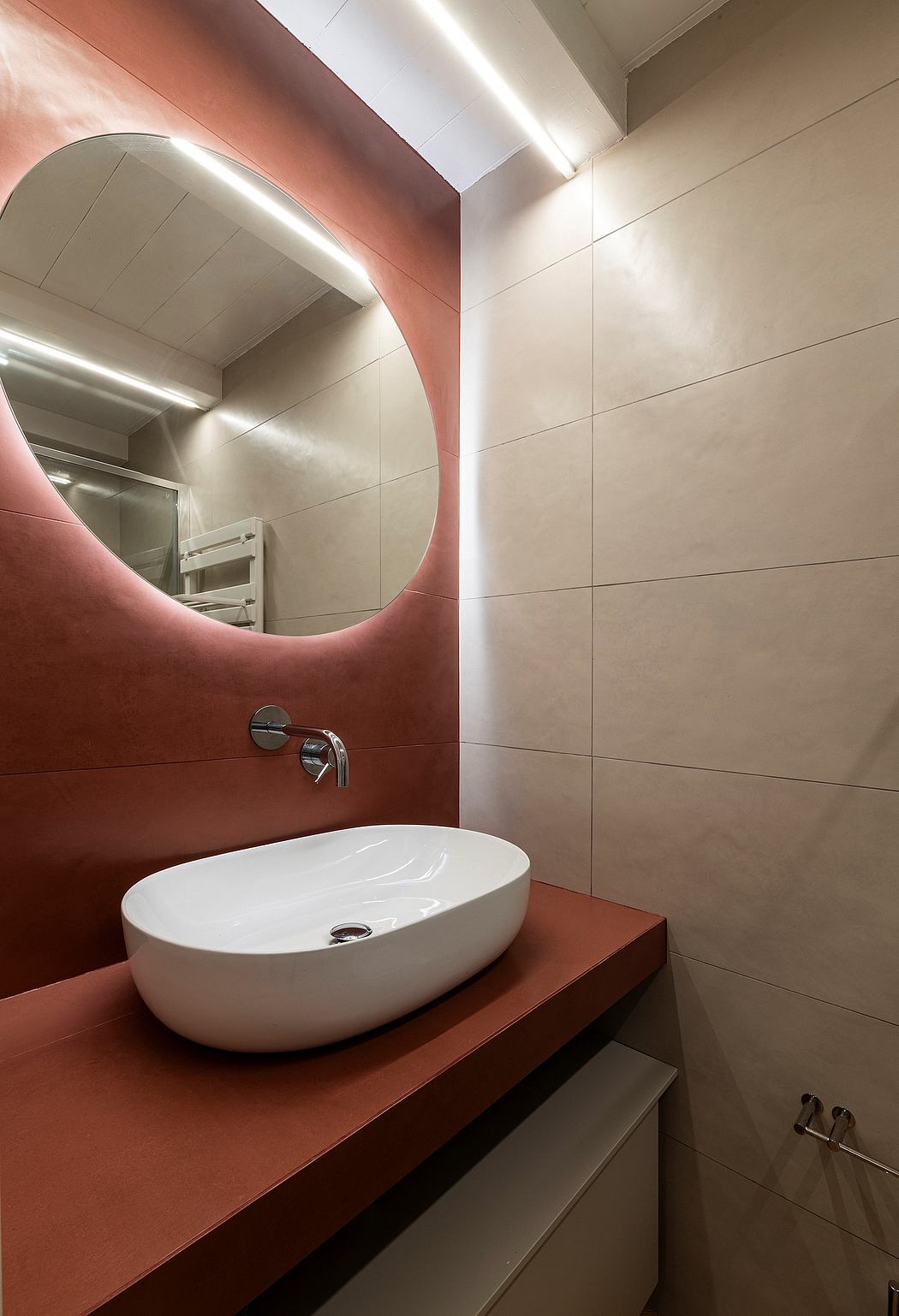 Modern, minimalist bathroom with curved pink wall, rectangular white sink, wooden vanity.