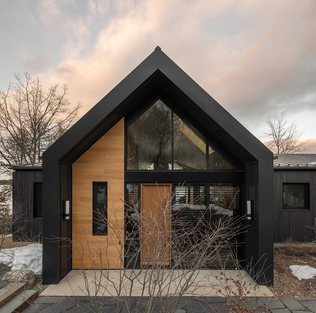 A modern cabin-like structure with a prominent pyramid-shaped roof, large windows, and a wooden facade.