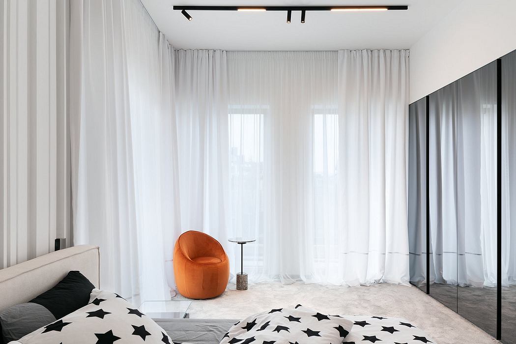 Bright, modern bedroom with sleek black furnishings, plush white carpet, and an orange accent chair.