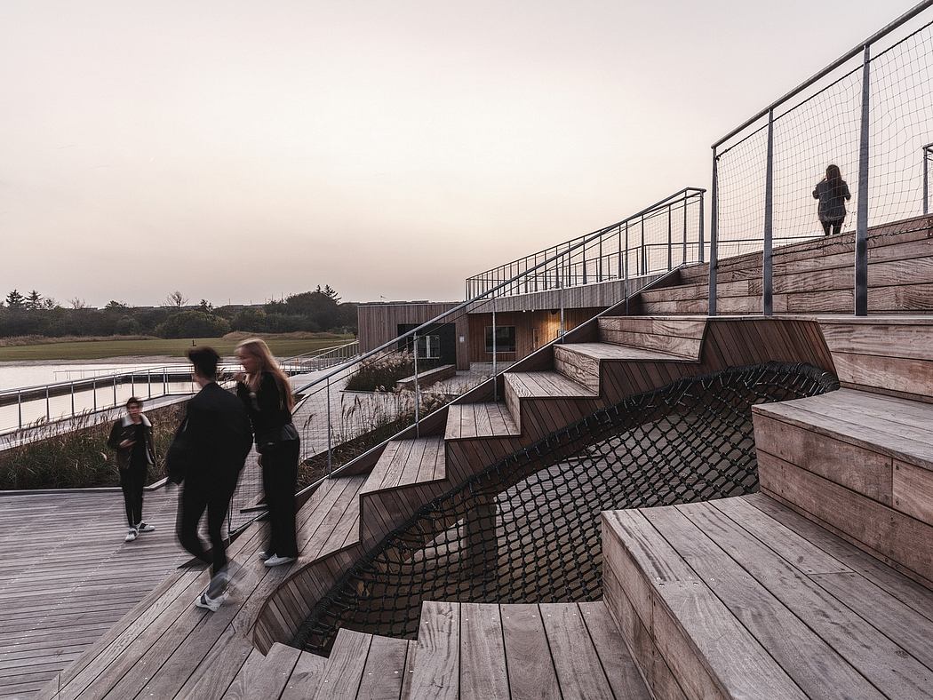 Wooden boardwalk and stairs with metal railings against a mountainous landscape.