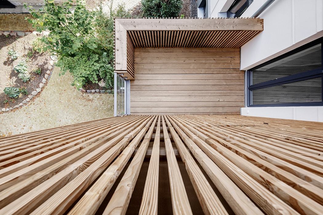 Wooden deck with slat pattern and covered overhead structure in a garden setting.