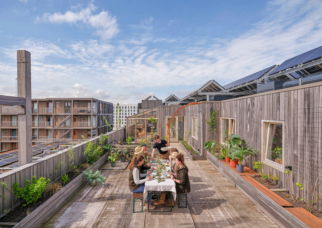 Wooden patio surrounded by plants and solar panels, with people dining together.