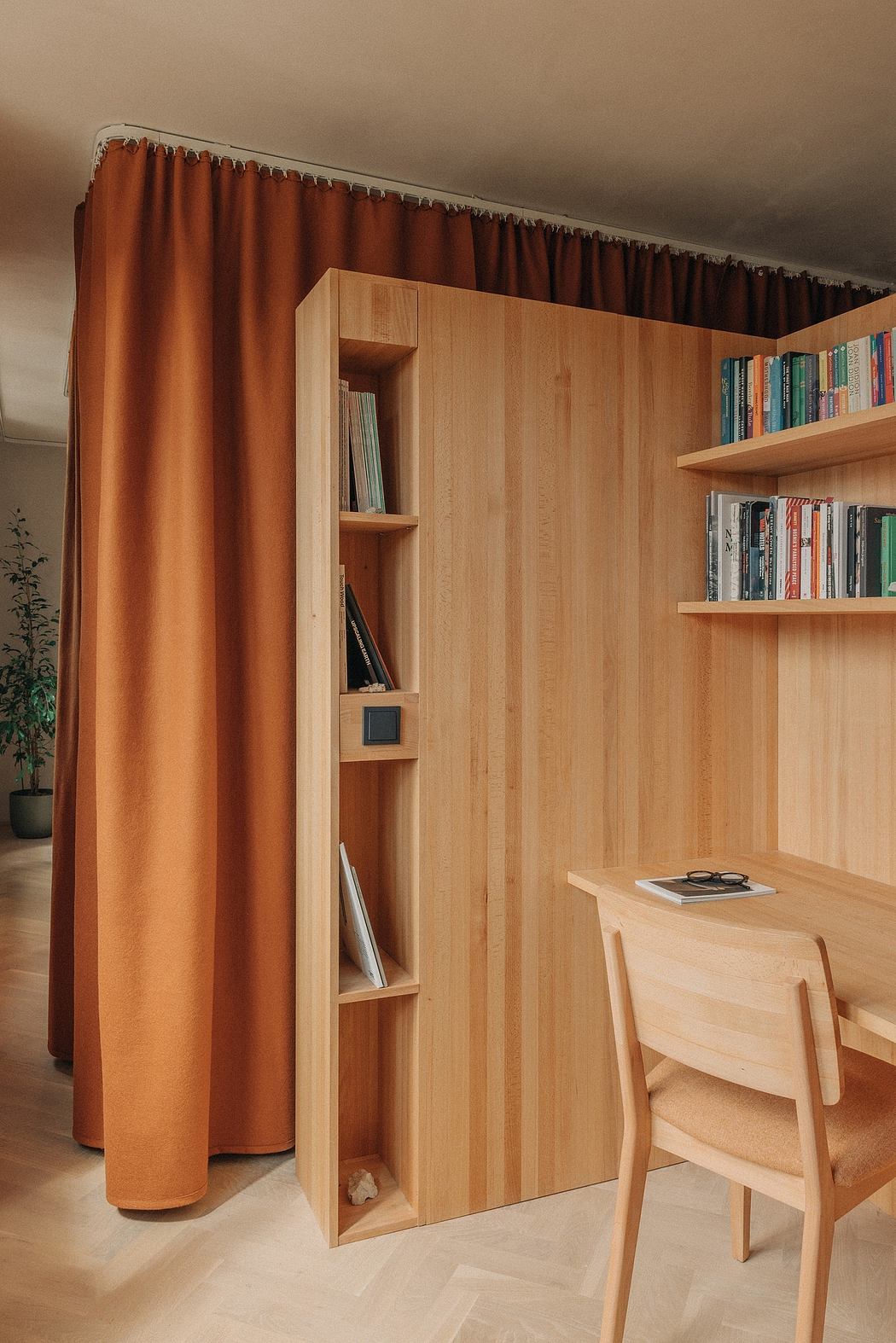Warm-toned wooden shelving and storage unit with a curtain partition in a cozy, minimalist space.