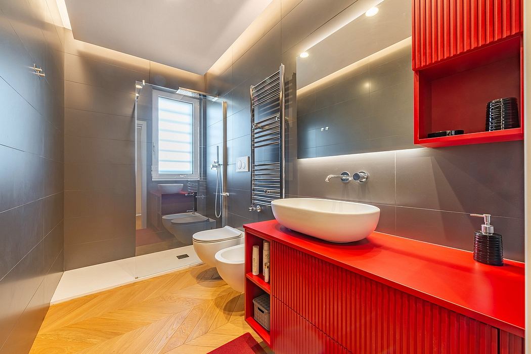 A modern bathroom with a red vanity, vessel sink, and linear lighting accents.