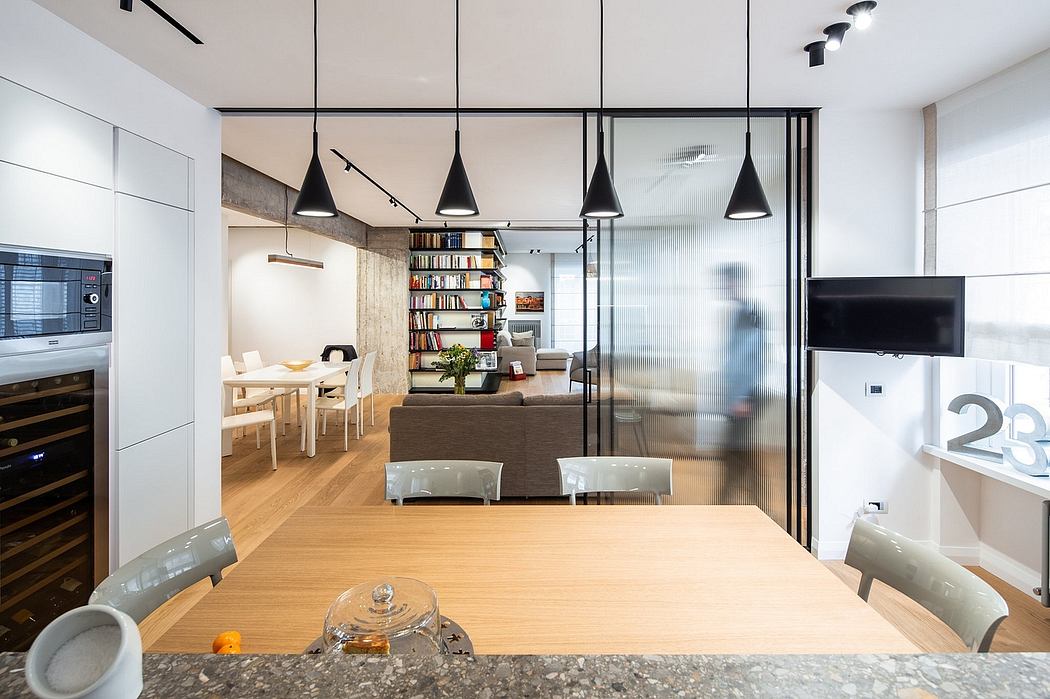 Sleek, modern kitchen and living room space with natural wood accents, hanging lamps, and built-in shelving.