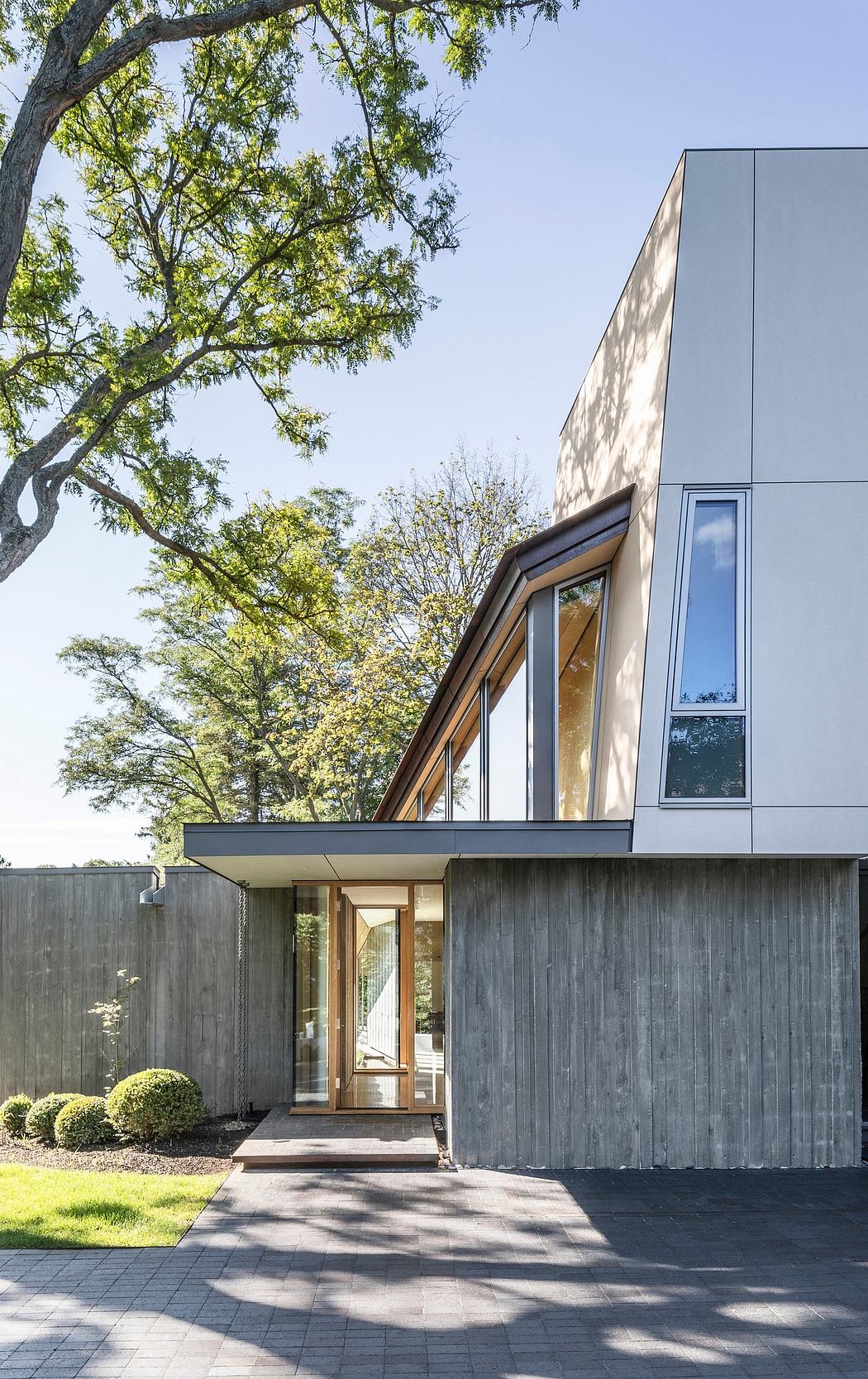 The modern home features a sleek exterior with geometric shapes, large windows, and a prominent roofline.