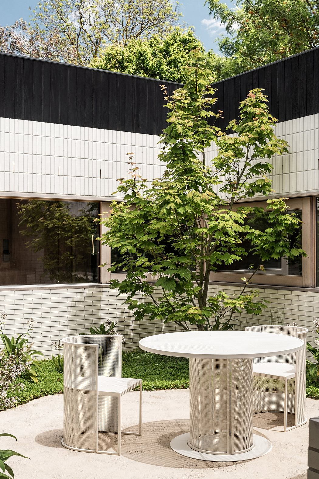 Sleek contemporary building with minimalist outdoor seating area and lush greenery.